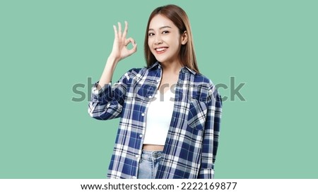 Happy beautiful Asian girl make OK hand sign and smiling isolated on mint green background with copy space.