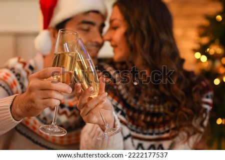 Young couple in love with glasses of champagne at home on Christmas eve, closeup