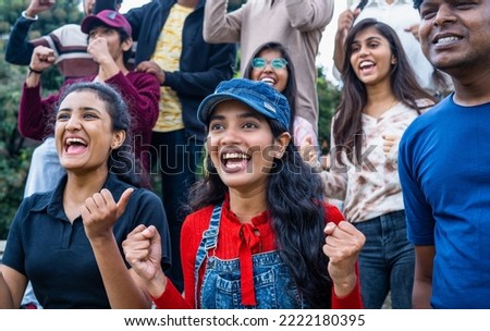 excited girl with audience at stadium cheering by celebrating win by shouting while watching live cricket sports match - concpet of happiness, entertainment and championship.