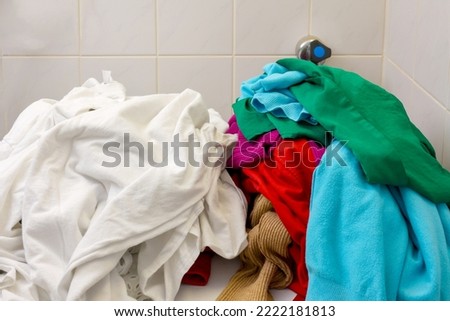 Pile of white and colors clothes being separate before load in to watching machine. Sort laundry before washing concept. Royalty-Free Stock Photo #2222181813