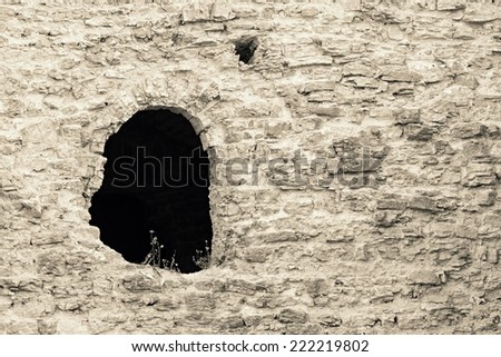 fragment of an ancient stone fortification of beige color with the destroyed window opening