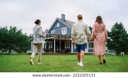 Young Couple Viewing Property for Sale, Talking with Professional Real Estate Agent Outside the House on a Summer Day. Young Beautiful Family are Ready to Become New Homeowners. Royalty-Free Stock Photo #2222205131