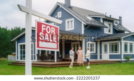 Young Couple Visiting a Potential New Home Property with Professional Real Estate Agent. Female Realtor Showing the Area to Future Homeowners. Focus on For Sale Sign. Royalty-Free Stock Photo #2222205237
