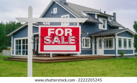Close Up of a Red House for Sale Sign on a Lawn in Front of a Big Modern House with Traditional Architecture. Housing Market Concept with Residential Property on Sale in the Countryside.