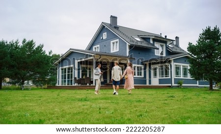 Real Estate Agent Showing a Beautiful House to a Young Happy Couple. People Walking Outside on a Lawn, Talking with Businesswoman, Discussing Buying a New Home. For Sale Sign on the Street. Royalty-Free Stock Photo #2222205287