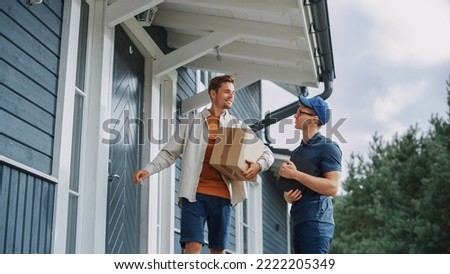 Handsome Young Homeowner Receiving an Awaited Parcel from a Cheerful Courier. Postal Service Worker Comes to the House to Make a Door to Door Delivery and Get a POD Signature on Tablet. Royalty-Free Stock Photo #2222205349