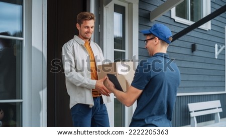 Handsome Young Homeowner Receiving an Awaited Parcel from a Cheerful Courier. Postal Service Worker Comes to the House to Make a Door to Door Delivery and Get a POD Signature on Tablet. Royalty-Free Stock Photo #2222205363