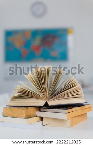 A thick open book on the table. School composition on the background of the world map. The concept of teaching, learning and education at the university, school and college. Close-up, space for text.