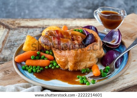 Toad in the hole with Yorkshire pudding, sausages and vegetables Royalty-Free Stock Photo #2222214601