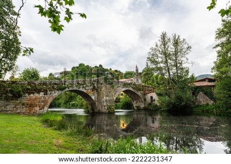 Medieval Roman bridge reflected on the water of the river Arnoia in the Galician village of Allariz on a rainy morning.