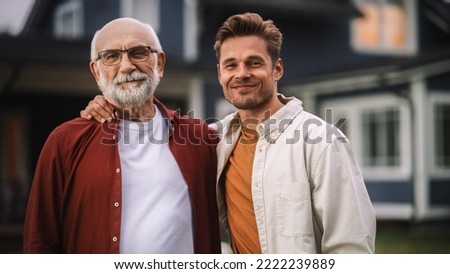 Portrait of a Happy Senior Father or Grandparent Posing Together with His Handsome Adult Son. Family Members Embrace Each Other, Standing, Looking at Camera and Smiling. Royalty-Free Stock Photo #2222239889