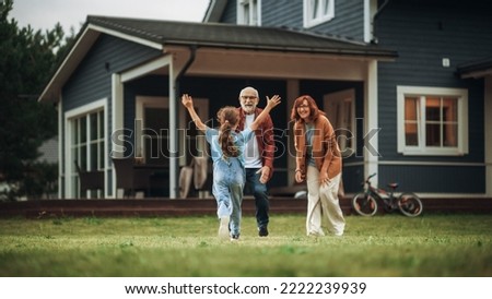 Grandfather and Grandmother are Happy to Meet Their Granddaughter in Front of their Suburbs House. Grandparents Spending the Weekend with Kids, Enjoying Family Time with Grandchild. Royalty-Free Stock Photo #2222239939