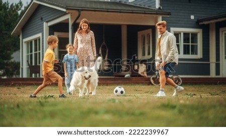 Joyful Young Couple with Kids, Playing Ball with an Energetic White Golden Retriever. Cheerful People Playing Football with Pet Dog on a Lawn in Their Front Yard in Front of the House. Royalty-Free Stock Photo #2222239967