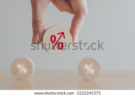 Interest rate finance and mortgage rates concept. Hand holding wooden circle with percentage sign arrow rise, financial growth, interest rate increase, inflation, sale price and tax rise concept.