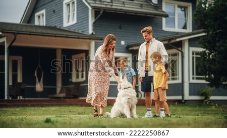 Portrait of a Cheerful Family Couple with Kids, Playing and Petting a Beautiful White Golden Retriever Dog. Happy Successful People Standing on a Lawn in Their Front Yard in Front of the House. Royalty-Free Stock Photo #2222250867