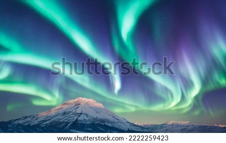 Northern Lights over snowy mountains. Aurora borealis with starry in the night sky. Fantastic Winter Epic Magical Landscape of snowy Mountains.   Royalty-Free Stock Photo #2222259423