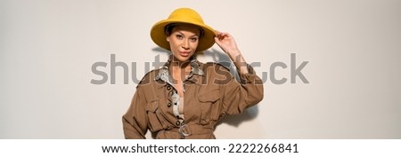 happy archaeologist in beige jacket adjusting safari hat on grey background, banner