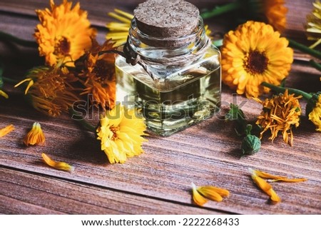 Calendula oil in glass bottle, Calendula officinalis , marigold flowers on wooden table