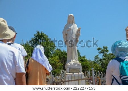 A group of Catholic pilgrims pray at a holy place. Pilgrims in Medjugorje, Bosnia and Herzegovina. Statue of Virgin Mary.  Royalty-Free Stock Photo #2222277153