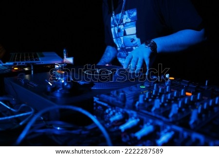 Hip hop dj scratching records on turntables. Disk jokey scratches vinyl record on turntable in nightclub. Professional disc jockey mixing music on party in night club. Download stock photo with DJ  Royalty-Free Stock Photo #2222287589