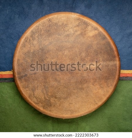 handmade, native American style, shaman frame drum covered by goat skin against colorful abstract paper landscape Royalty-Free Stock Photo #2222303673