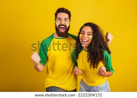 couple of brazil soccer supporters, dressed in the colors of the nation, black woman, caucasian man. Twisting and vibrating. Royalty-Free Stock Photo #2222304131