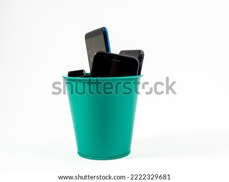 Full trash can of old smartphones on a white background. Electronics recycling concept. Royalty-Free Stock Photo #2222329681