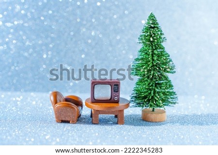 Creative Christmas card background: miniature furniture and TV-set placed by the toy new year tree.