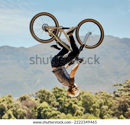 Mountain bike, man and upside down air jump, action and bicycle stunt, challenge and adventure, freedom or dynamic risk in sky. Biker athlete, sports adrenaline and energy in outdoor competition show Royalty-Free Stock Photo #2222349465
