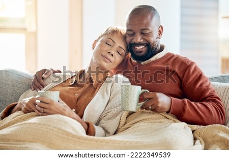 Black couple relax on sofa with coffee, blanket and smile on winter weekend morning in home. Peace, comfort and love, happy man and tired woman, cozy time on couch with drink in living room together. Royalty-Free Stock Photo #2222349539