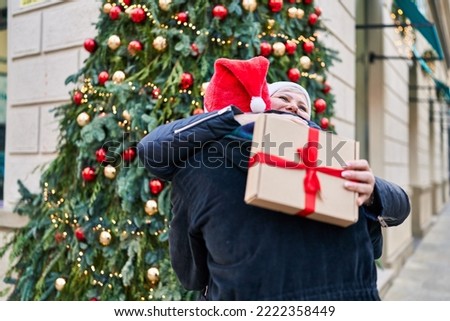 Mother and son hugging each other holding christmas gift at street