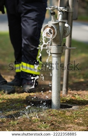 Draining water from a fire hydrant with a firefighter in the background