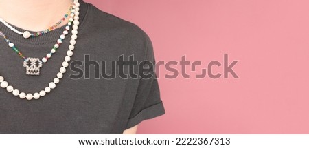 Banner with multicolored pearl beads on a young woman in front of pink pastel background. Selective focus. Place for text.