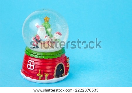 Blue Christmas background with snow globe with Santa, snowman and Christmas tree with copy space