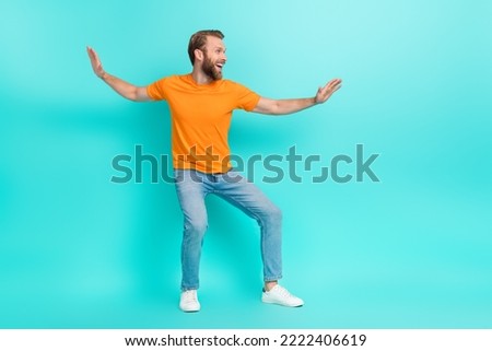 Side profile photo of handsome positive man muscular beard wear orange t-shirt jeans look empty space isolated on teal color background