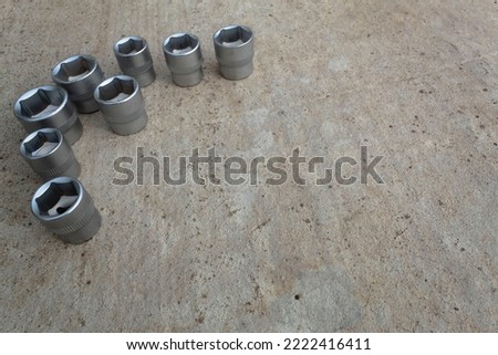 Socket heads of various sizes lie on the concrete surface. Copying text or logo for presentation. Industrial background from tools.