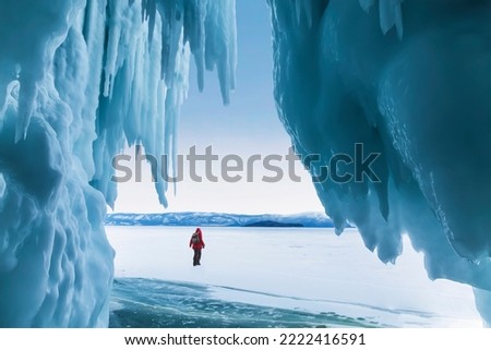An ice cave on the frozen Lake Baikal and a lonely tourist. Eastern Siberia, Russia