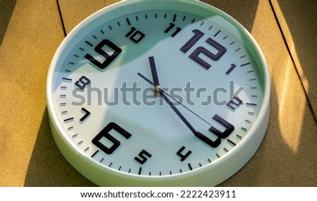 Wall clock show the time. A modern wall clock.  Close up to a wall clock, with black time pointer and red second pointer. Sun and sky reflecting in the watch during the time passing by