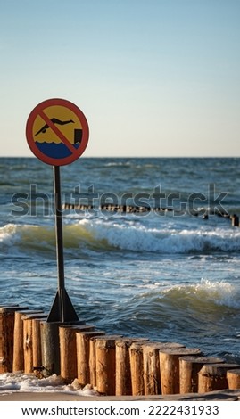 Wooden breakwaters. Sign forbidding jumping from breakwaters into the sea. Beach hazard warning sign.