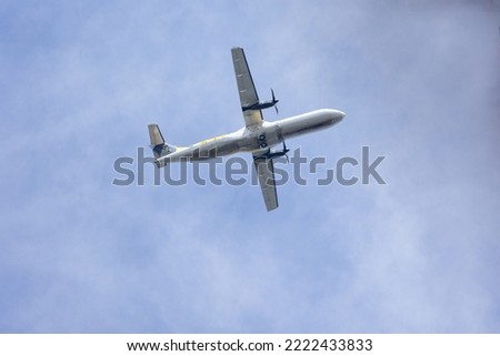 A twin-engine plane flying in a blue sky between clouds. Transportation.