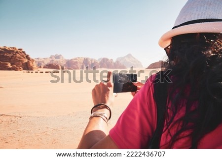 Female brunette caucasian tourist back view take image of Jordan desert landscape in wadi rum tour in hot summer day. Copy space background