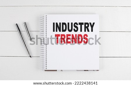 INDUSTRY TRENDS text written on a notebook on the wooden background