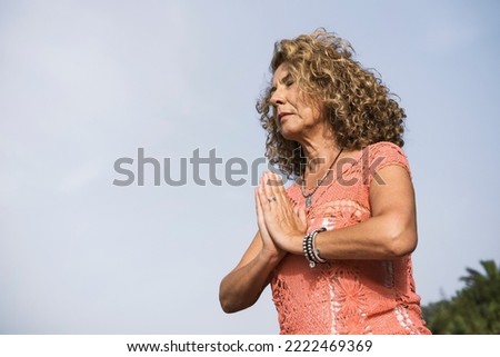 mature woman meditating on the beach