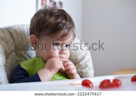 little baby having tomatoes in the high chair