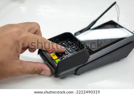 Person hand is pressing the enter button to confirm payment transaction on the credit card reader device. Business and technology action scene photo, selective focus.