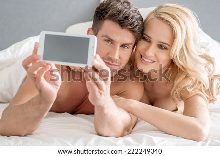 Middle Age Romantic Lovers Taking Sweet Photos on Bed with White Cover.