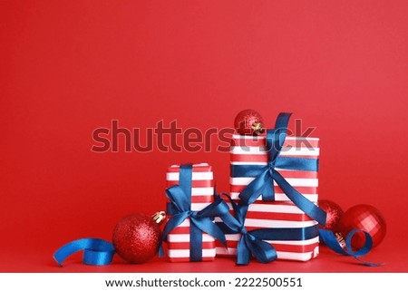 Wallpaper greeting card Merry Christmas holiday composition with blue striped gift box present toy ball decoration on red background. Xmas New Year winter design idea concept. Copy space for text