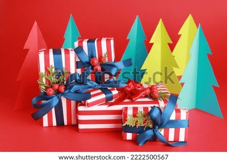 Wallpaper greeting card Merry Christmas holiday composition with blue white striped gift box present green pine fir tree decoration on red background. Xmas New Year winter design idea concept. 