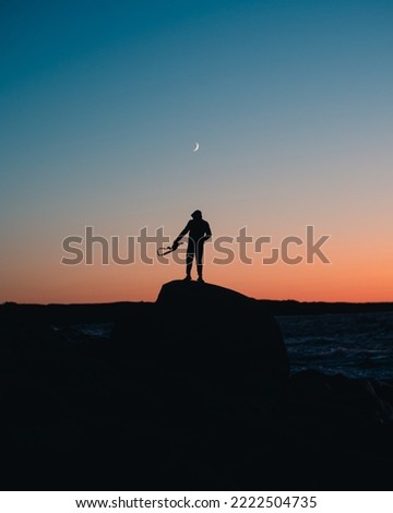 man standing under new crescent moon
