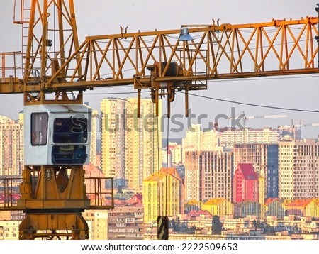 Construction cranes above the unfinished residential building against sunshine. Housing construction, apartment block in city
